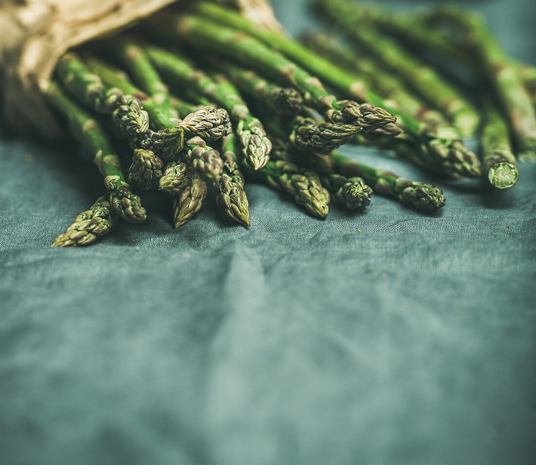 Fresh green asparagus over dark grey linen table cloth background