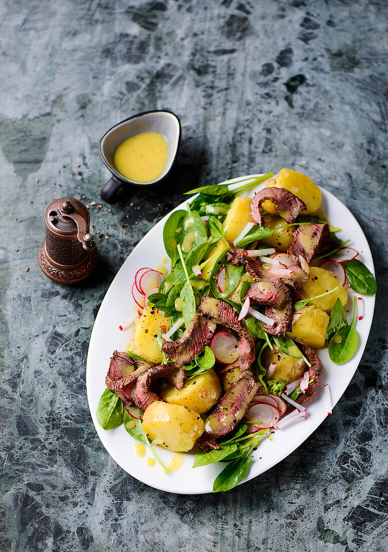 Potato salad with baby spinach and steak stripes