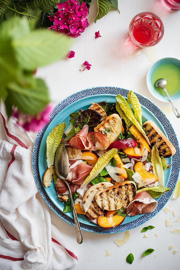 A mixed leaf salad with cured ham, nectarines, Parmesan and grilled bread