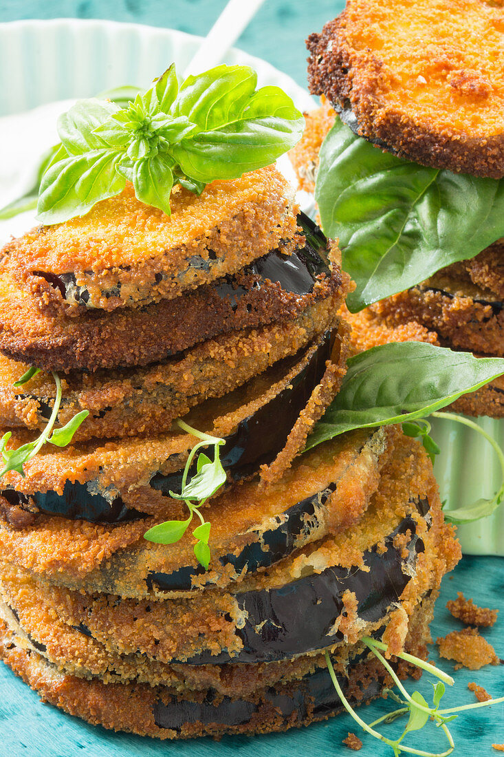 Fried aubergine slices, stacked, with fresh herbs