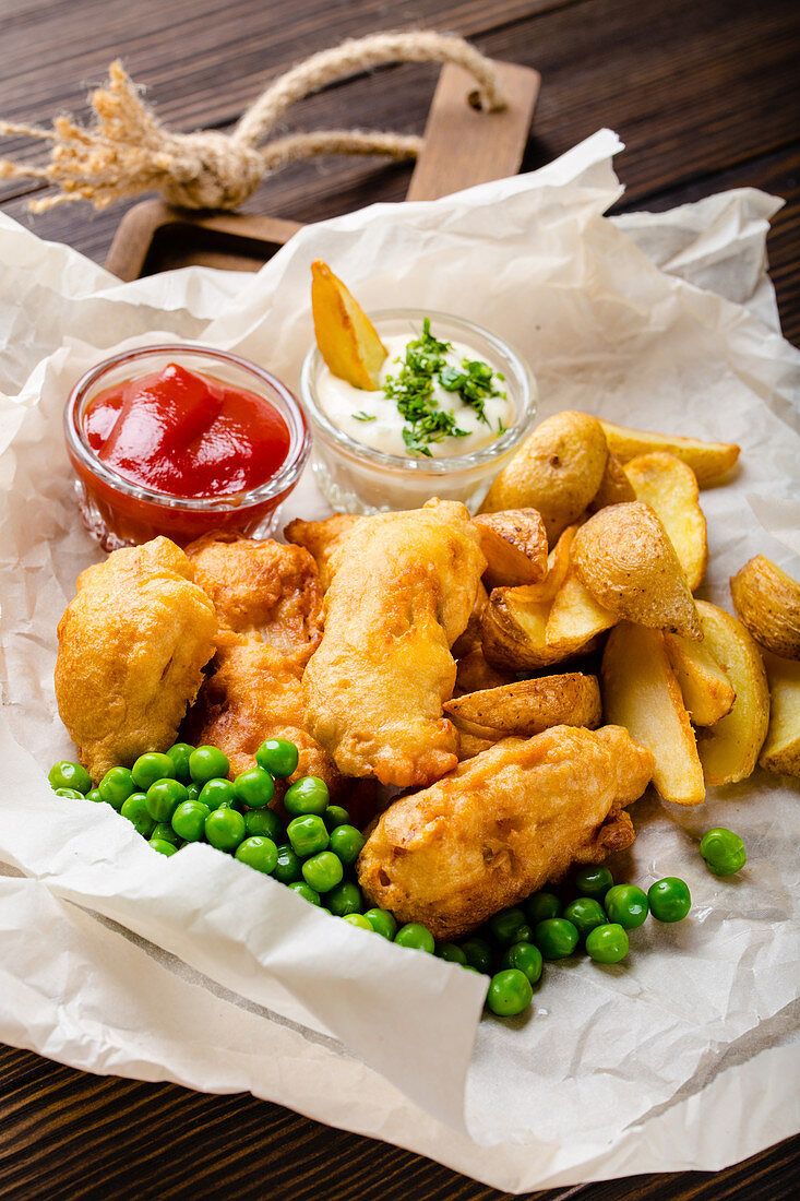 Fish and chips with peas and dips on paper (England)