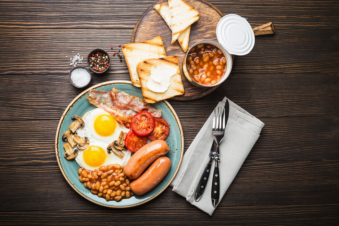 Englisches Frühstück mit Spiegeleiern, Speck, Würstchen, Bohnen und Toast