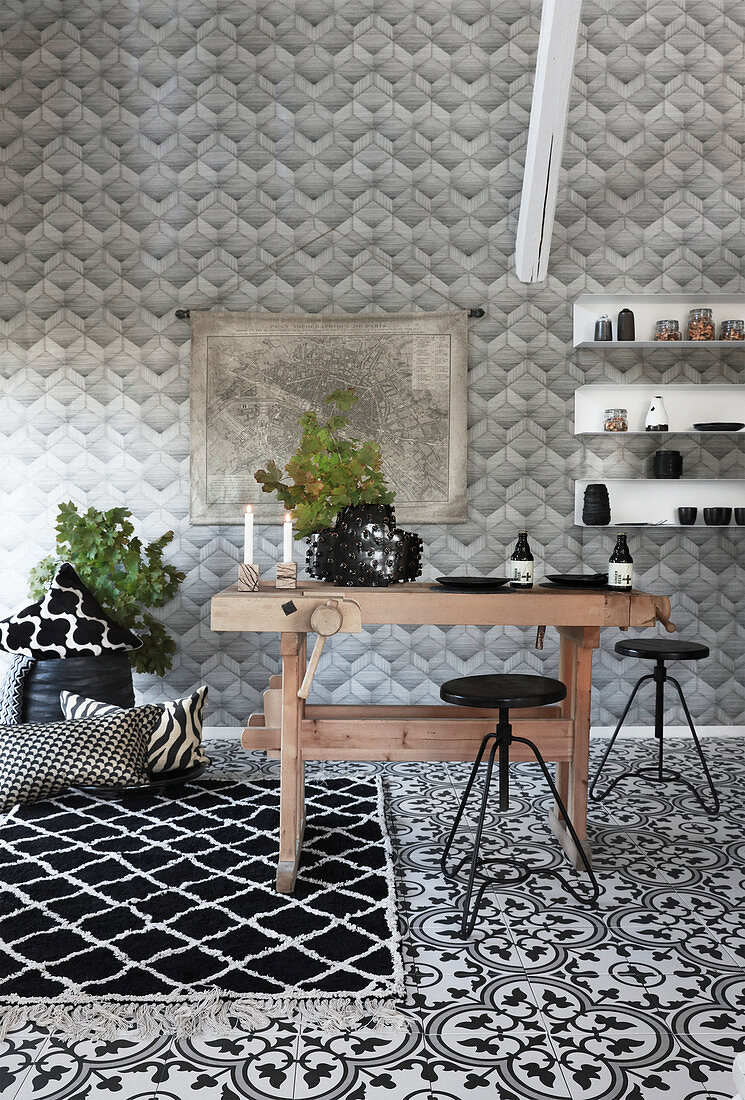 Rustic wooden table and black stools in black-and-white kitchen with various patterns