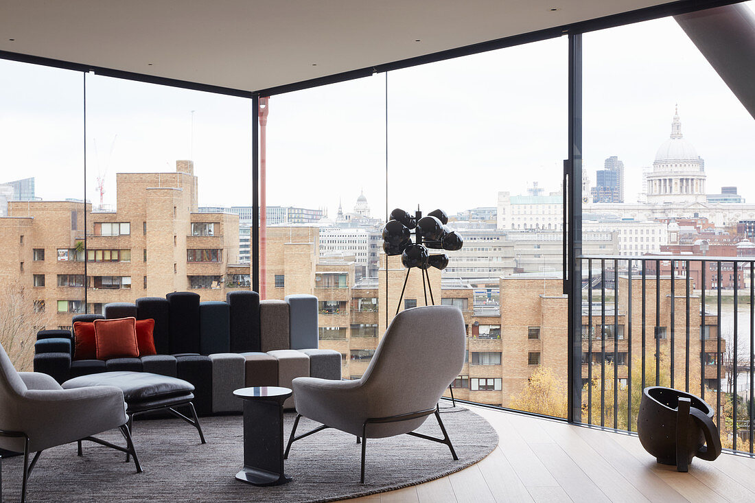 Elegant lounge in shades of grey in penthouse with glass walls