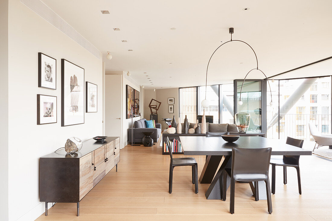 Sideboard, dining table and chairs in open-plan interior with glass wall leading onto balcony