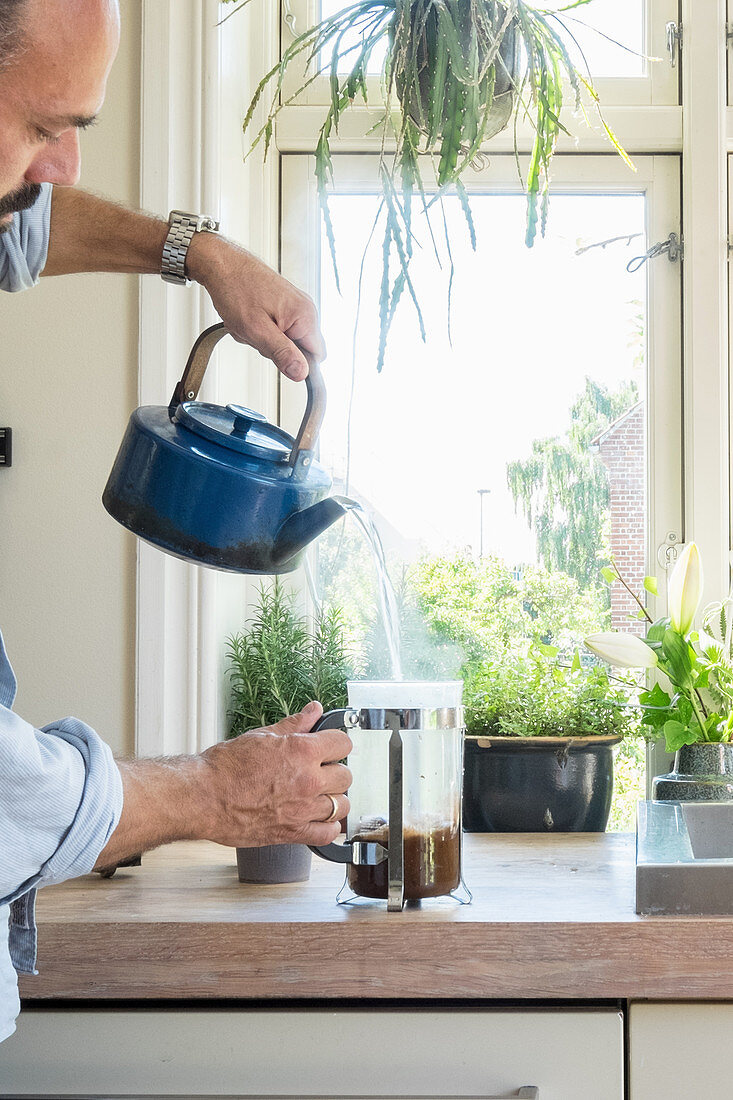 Mann gießt heißes Wasser in eine Kaffeekanne