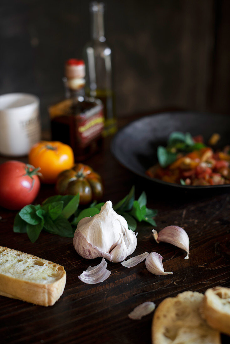 Stillleben mit Knoblauch, Tomaten, Basilikum und Brot