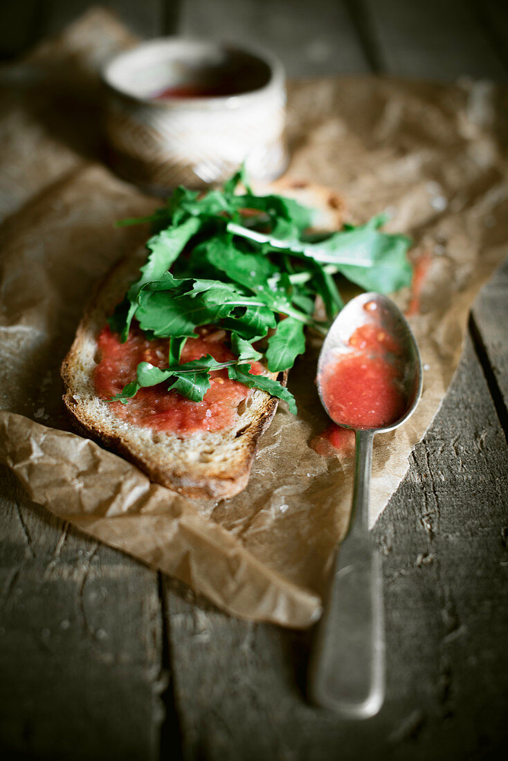 Sauerteigbrotscheibe mit roher Tomatensauce und Rucola