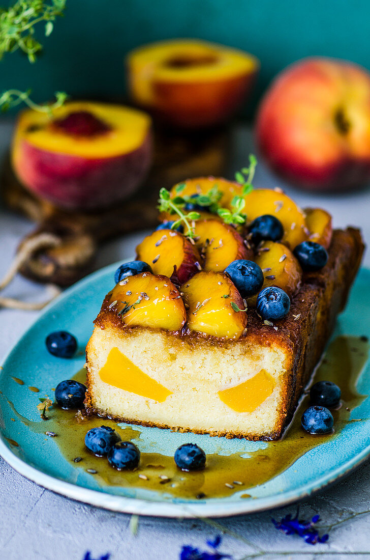 Angeschnittener Obstkuchen mit mit Pfirsichen, Blaubeeren, Lavendel und Thymian