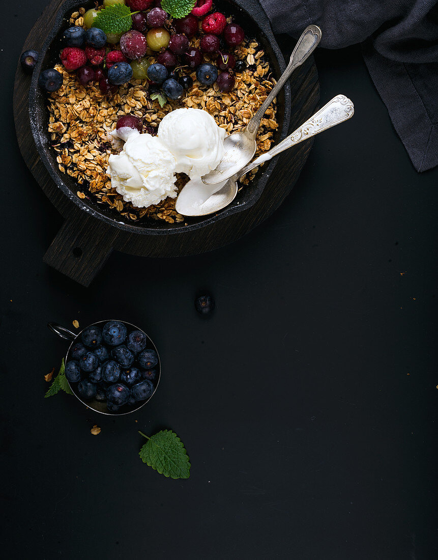 Healthy oat granola crumble with fresh berries, seeds, ice-cream and mint leaves