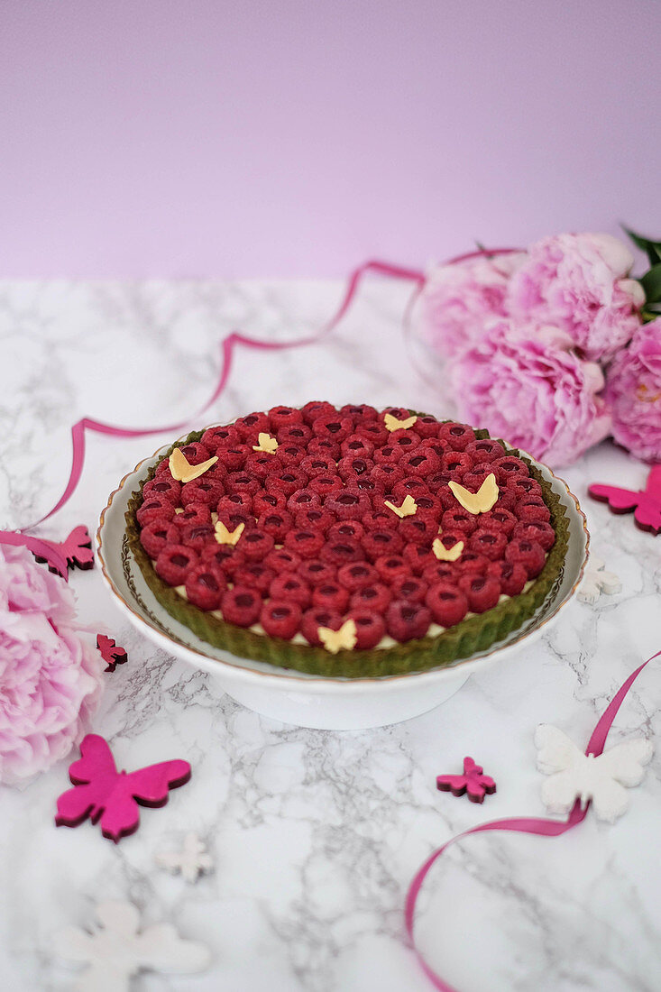 A raspberry tart with a green base and vanilla cream
