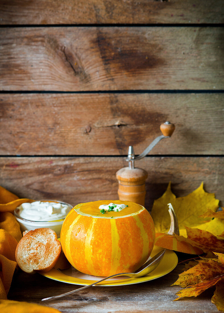 Herbstliche Kürbissuppe serviert in ausgehöhltem Kürbis