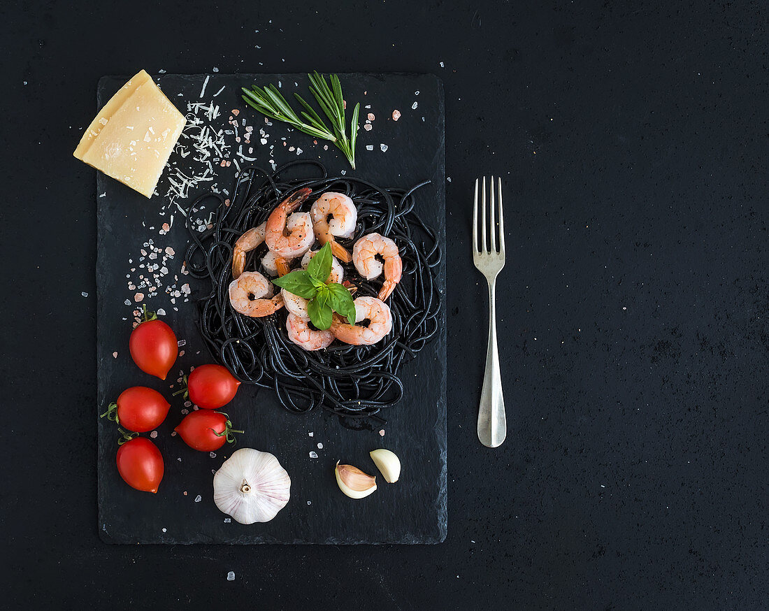 Schwarze Spaghetti mit Garnelen und Zutaten auf Schieferplatte