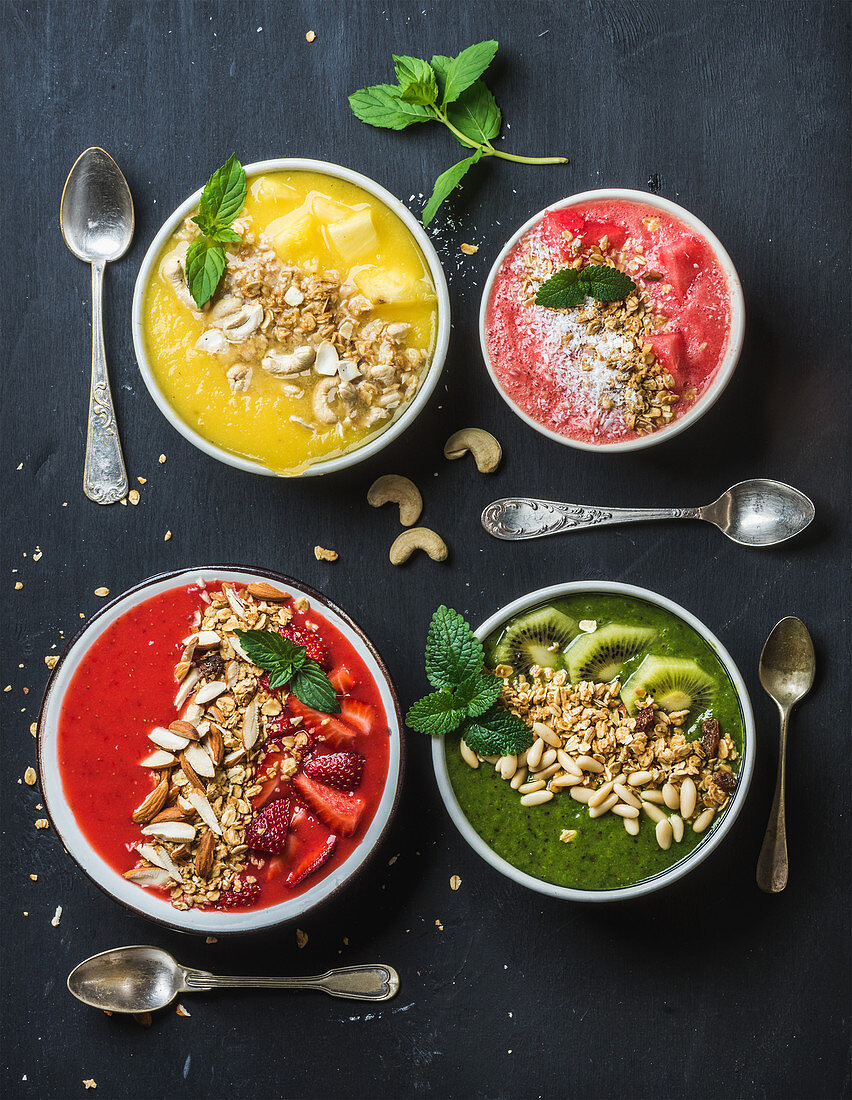 Healthy summer breakfast smoothie bowls with nuts, oat granola and mint leaves