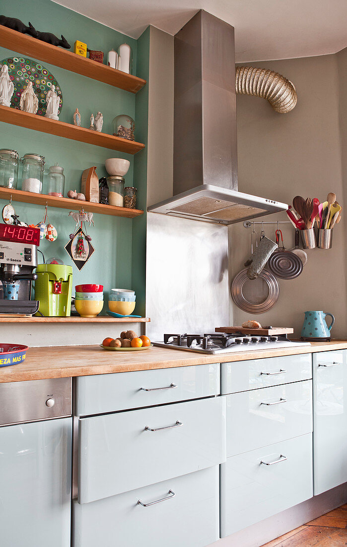 White kitchen counter with extractor hook and shelves on wall in green niche