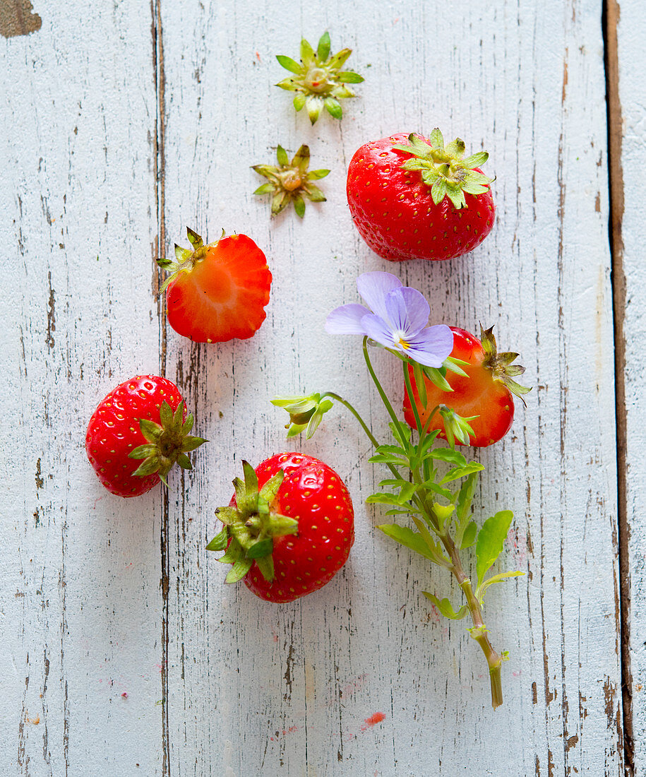 Frische Erdbeeren und Hornveilchen auf Holzuntergrund