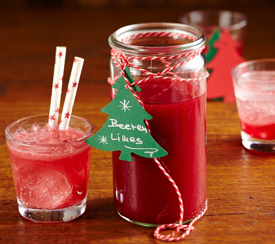Selbstgemachter Beeren-Limes aus gefrorenen Waldbeeren als Weihnachtsgeschenk in einem hohen Glas