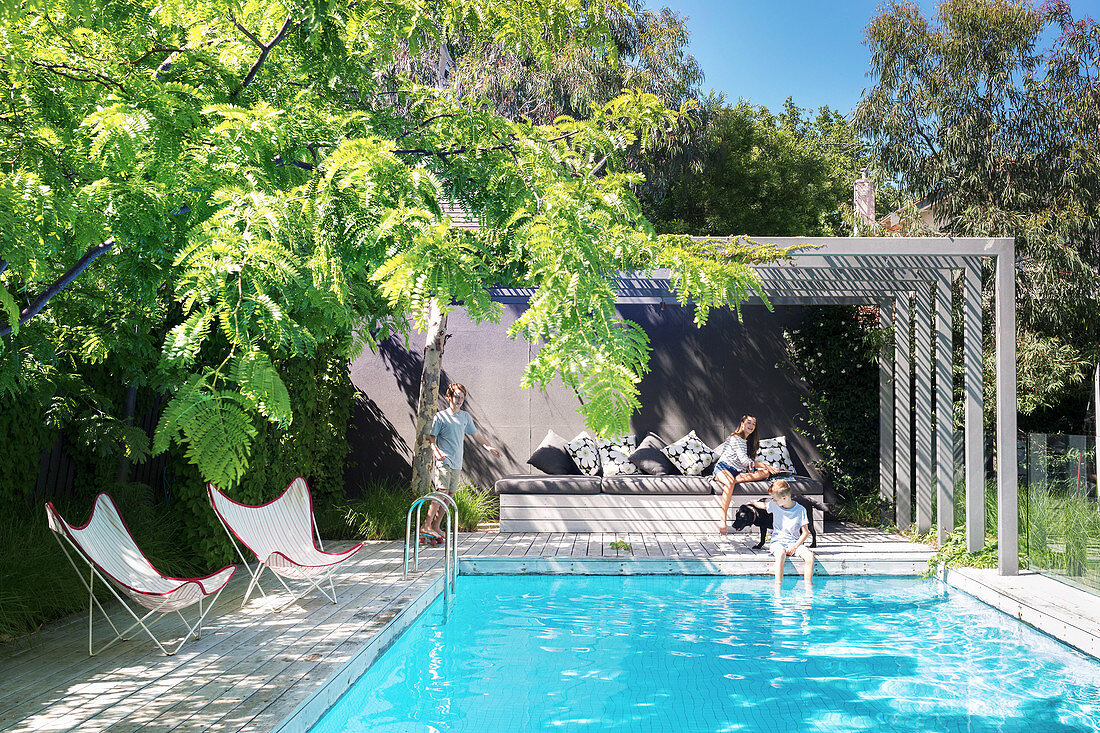 Familie mit Hund am Pool im Garten