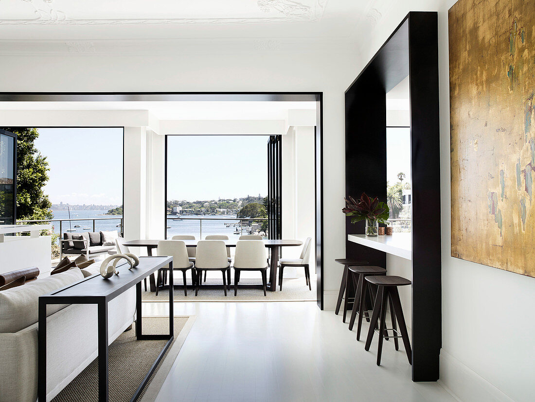 Counter with bar stools, dining area in front of window with sea view and lounge in designer style