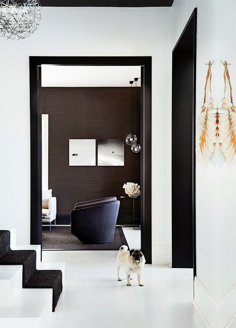 Hallway with white floor and staircase, view of the armchair in the living room