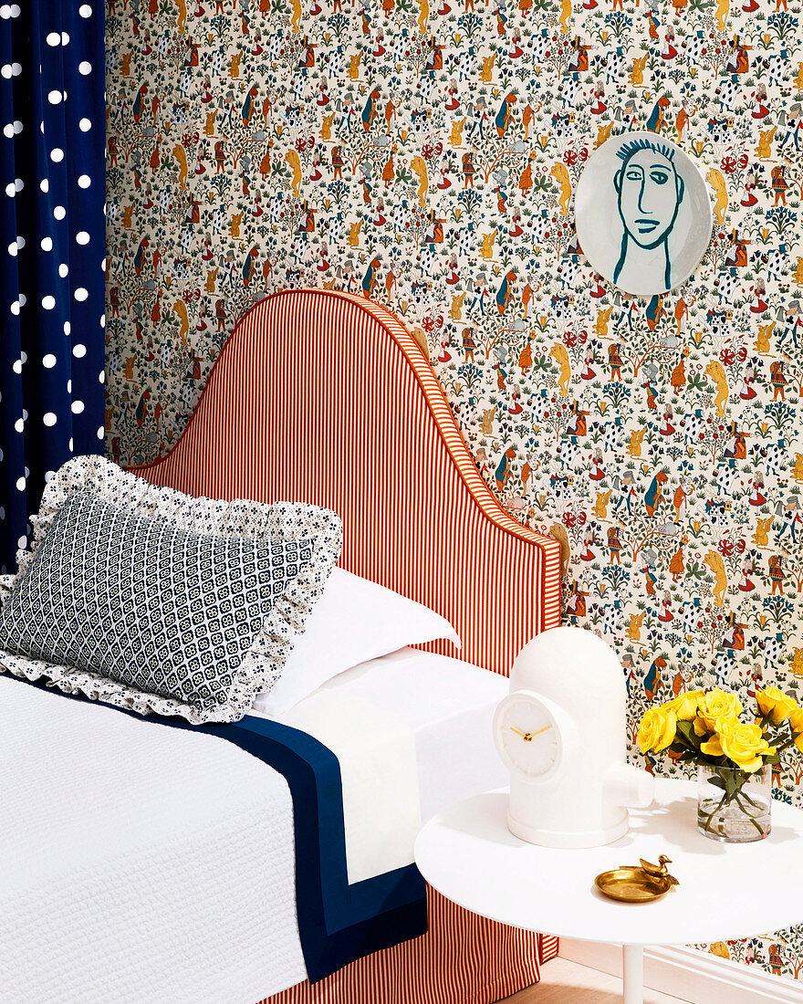 Bett mit gestreiftem Kopfteil vor Wand mit Designertapete
