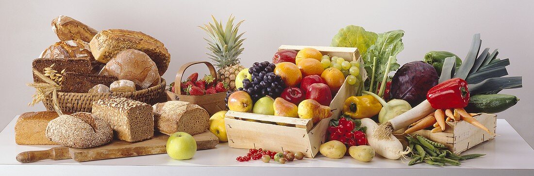 Stillleben mit Gemüse, Obst & Broten auf Tisch
