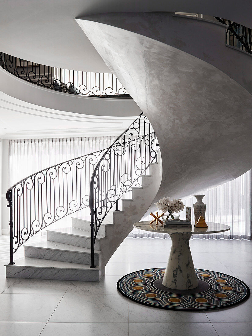 Elegant hall with spiral marble staircase and marble table