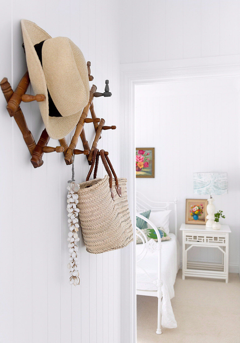 Hut und Tasche an Wandgarderobe, Blick ins weiße Schlafzimmer