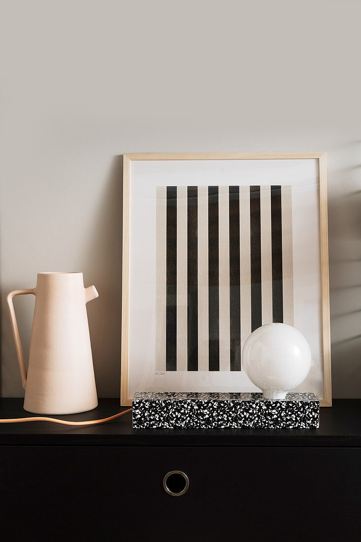 Hand-made designer lamp in front of striped artwork and next to jug