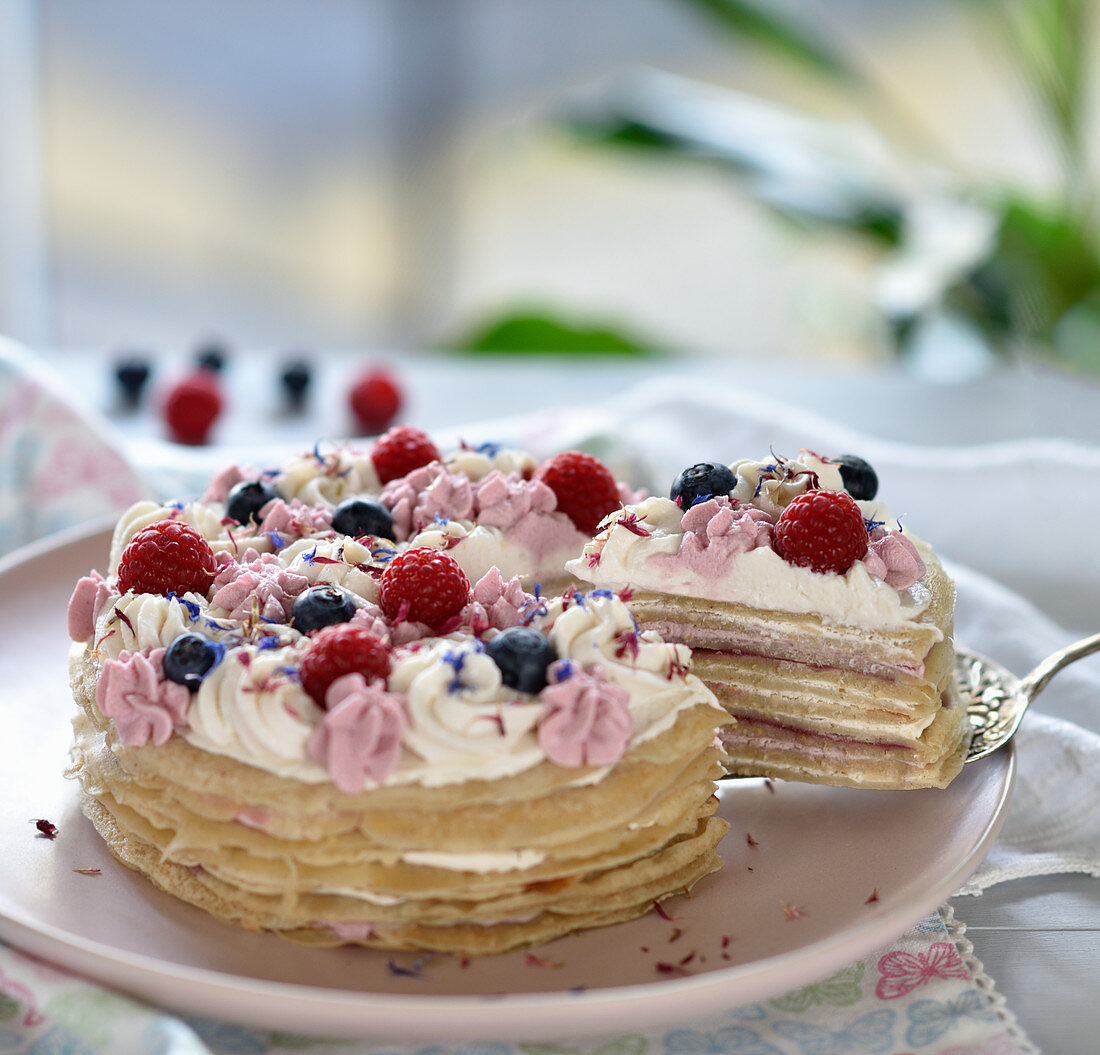 Vegan crêpes cake with two-tone cream, berries and dried flowers
