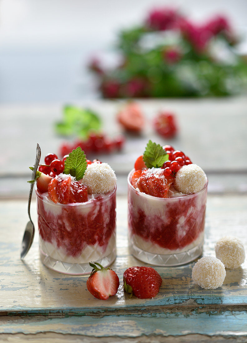 Veganes Kokos-Erdbeer-Dessert im Glas mit Kokosbällchen und frischen Beeren