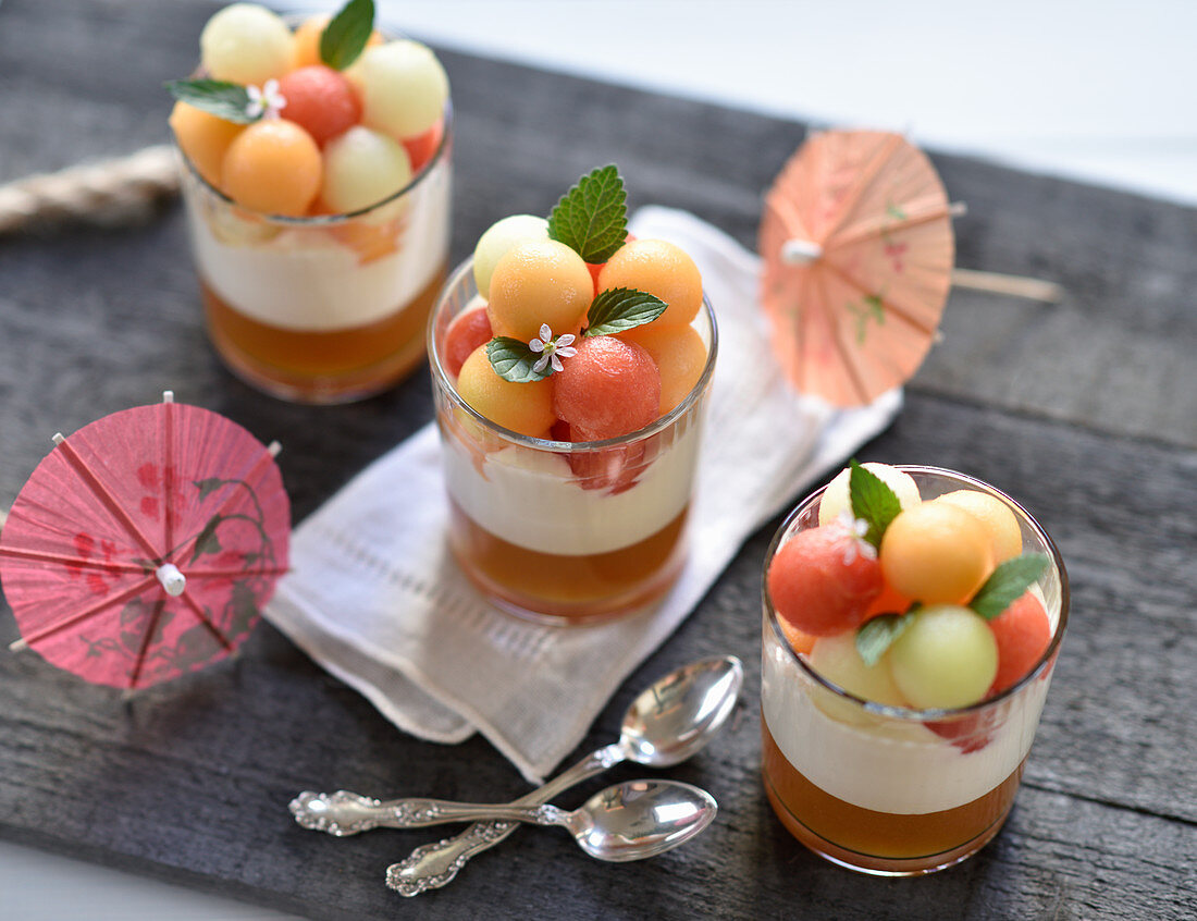 Vegan melon desserts in glasses with melon jelly, whipped sour cream and a trio of different coloured melon balls