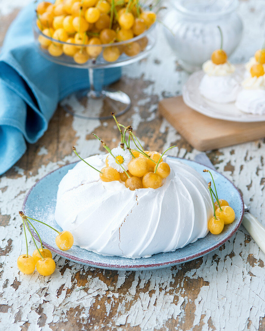 A pavlova with yellow cherries