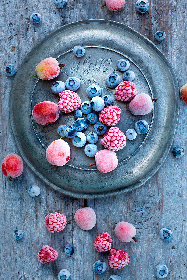 Gefrorene Blaubeeren, Stachelbeeren und Himbeeren auf altem Zinnteller