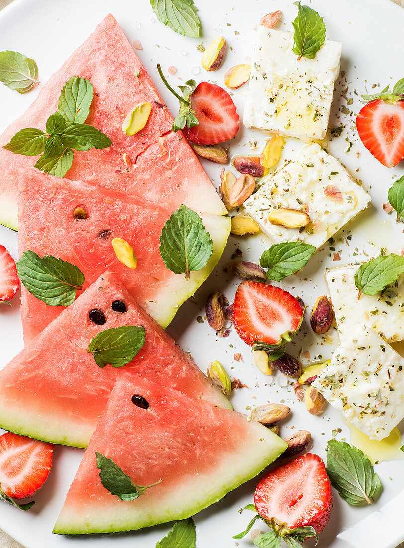 Summer watermelon, strawberry and feta cheese salad with mint leaves and pistachios