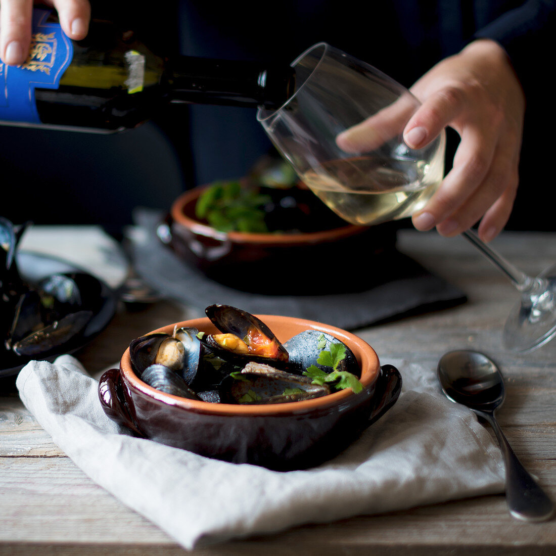 White wine being poured over a mussel dish