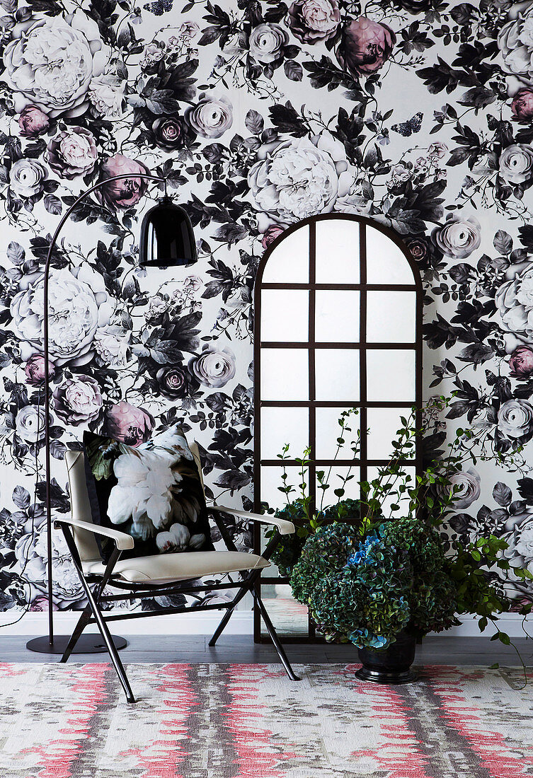 Chair and floor mirror against opulent floral wallpaper