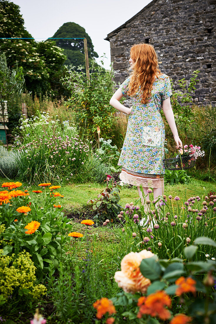 Rothaarige Frau im Blümchenkleid im Garten