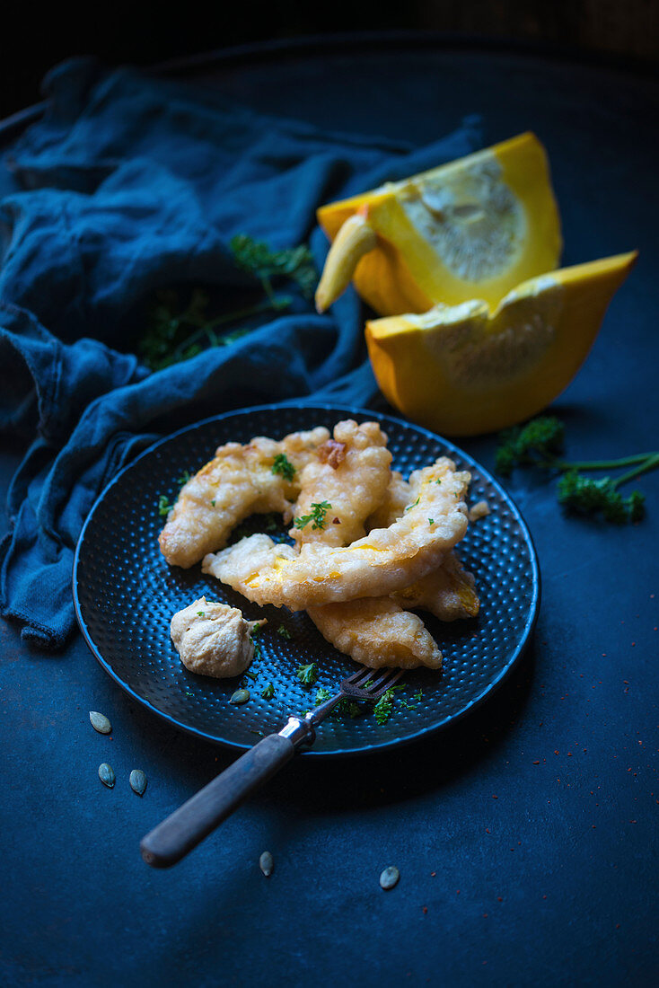 Frittierte Kürbisspalten im Bierteig, dazu Hummus