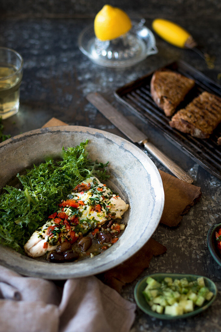 Seehecht mit Tomaten, Oliven und Knoblauch aus der Pfanne mit Grillbrot und Salat
