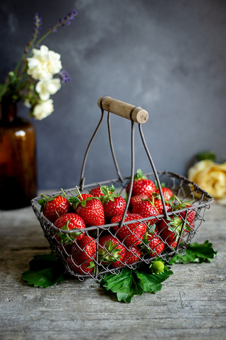 Fresh strawberries in a vintage wire basket on a dark surface