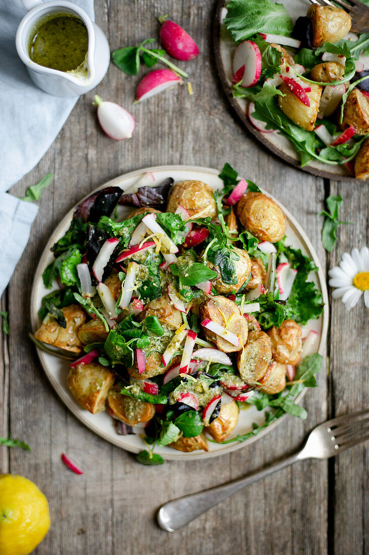 Roasted new potato salad with chopped radish and green pesto on a wooden backdrop