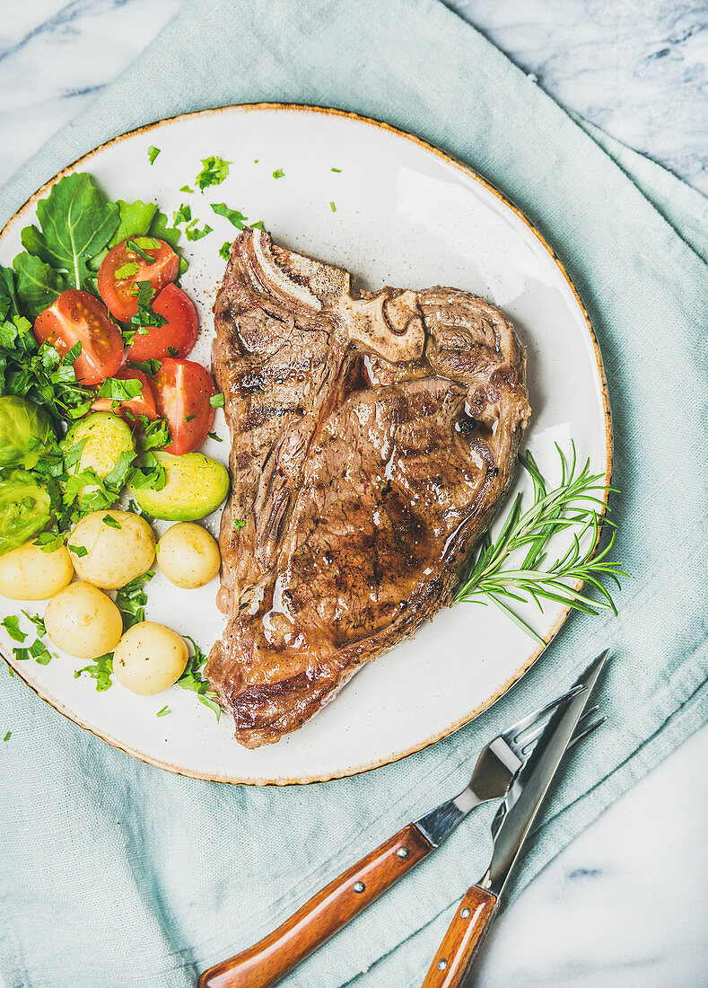 Grilled beef t-bone steak with vegetables and fresh rosemary