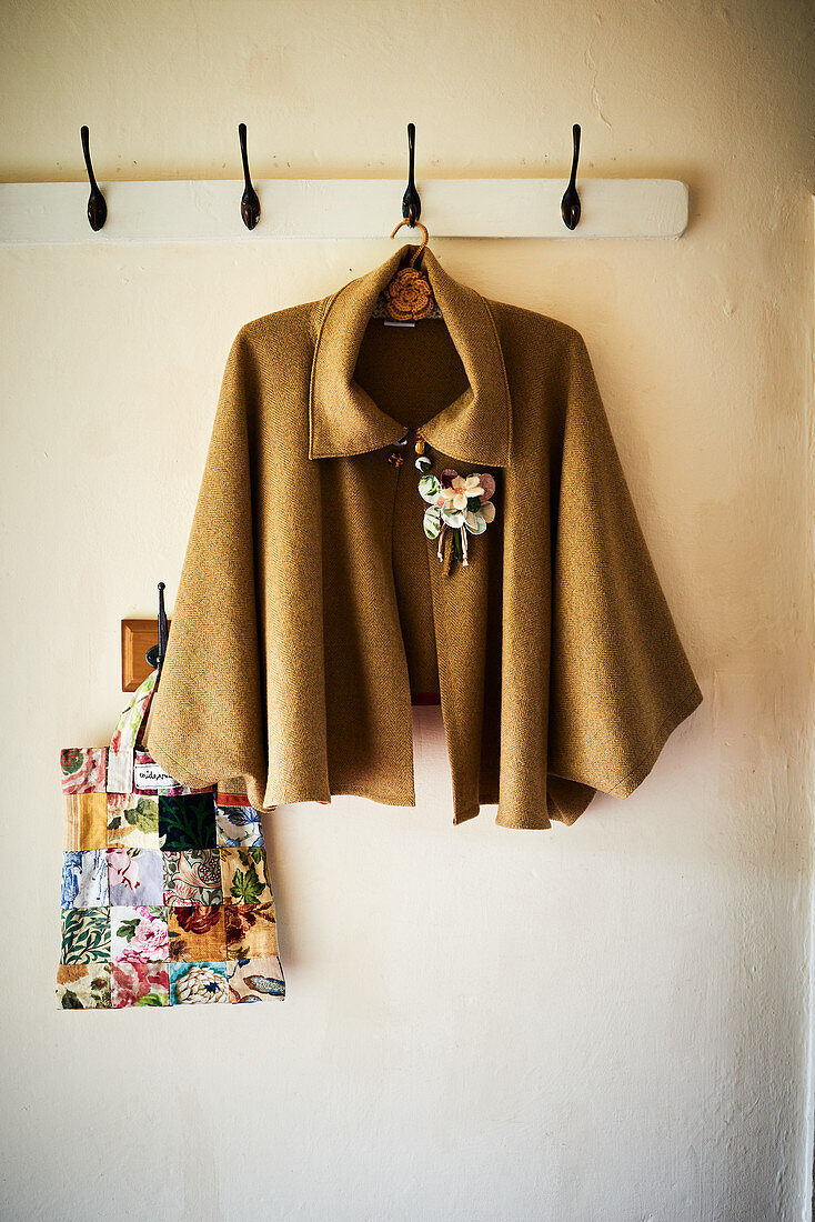 Cape with floral brooch hung from coat rack