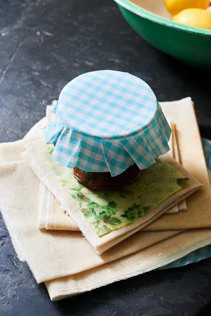 Ein Glas Marmelade mit blau-weiß kariertem Stoff