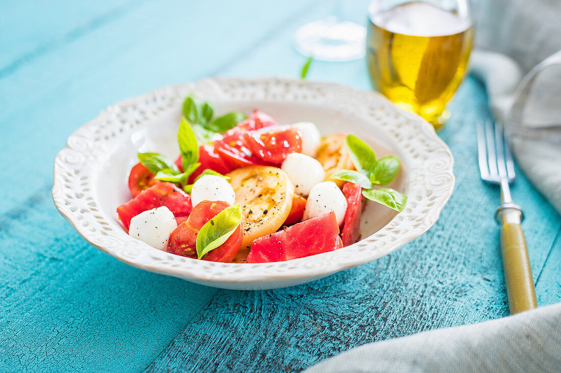 Simple summer caprese salad with mozzarella cheese, colouful tomatoes and fresh basil