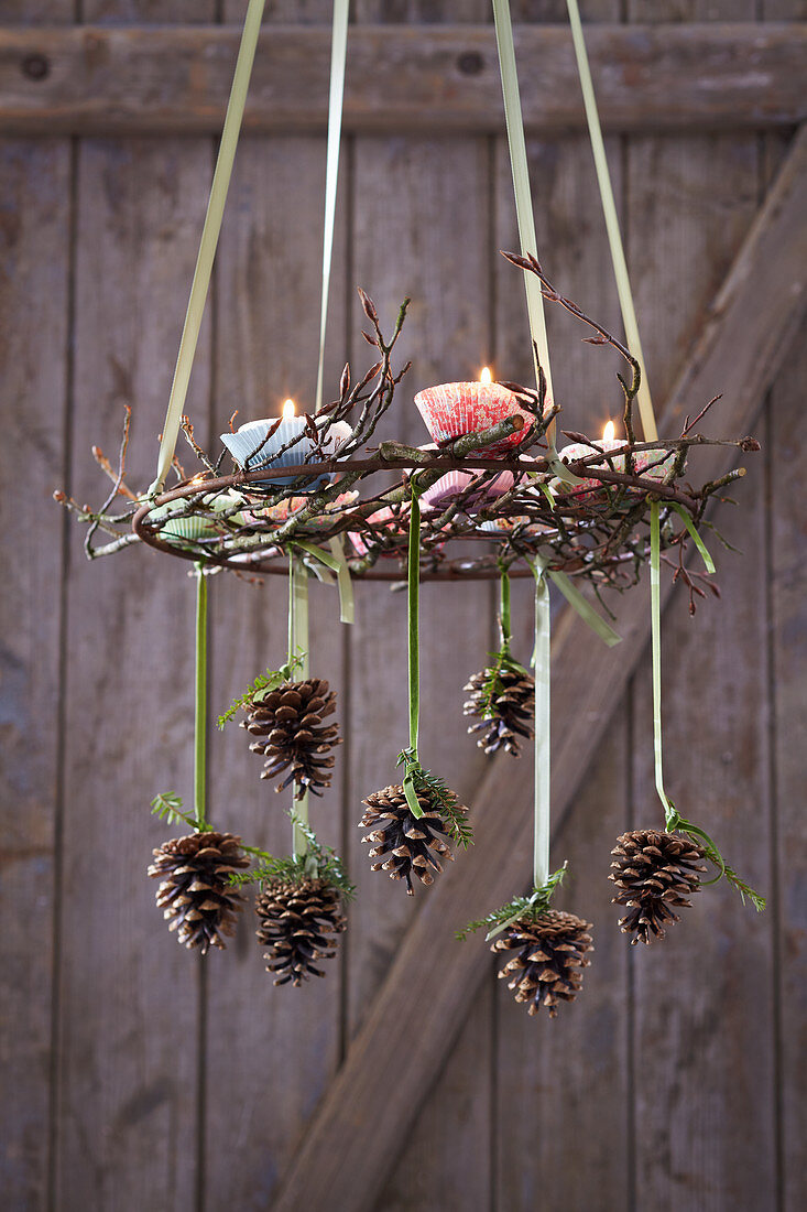 Suspended Advent wreath decorated with pine cones and candles in paper cake cases