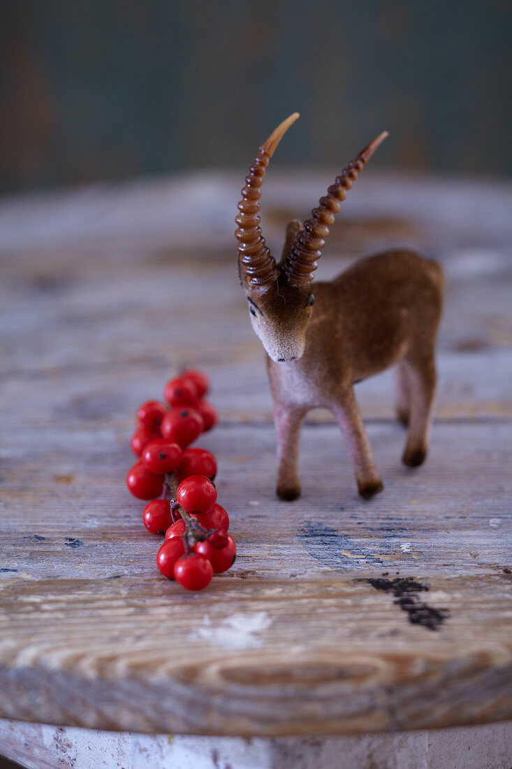 Rustic winter arrangement of ibex figurine and sprig of red berries