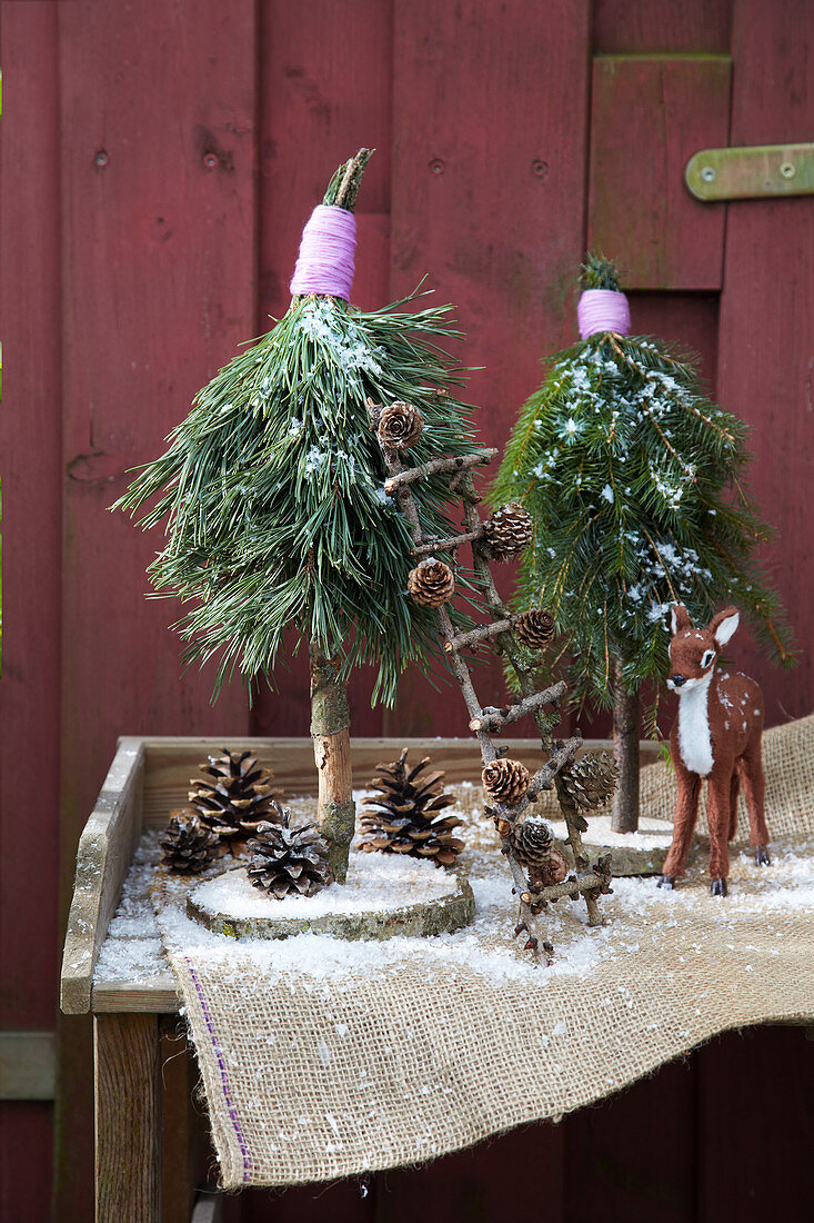 Small trees handmade from conifer branches and slices of tree trunk as wintry garden decorations