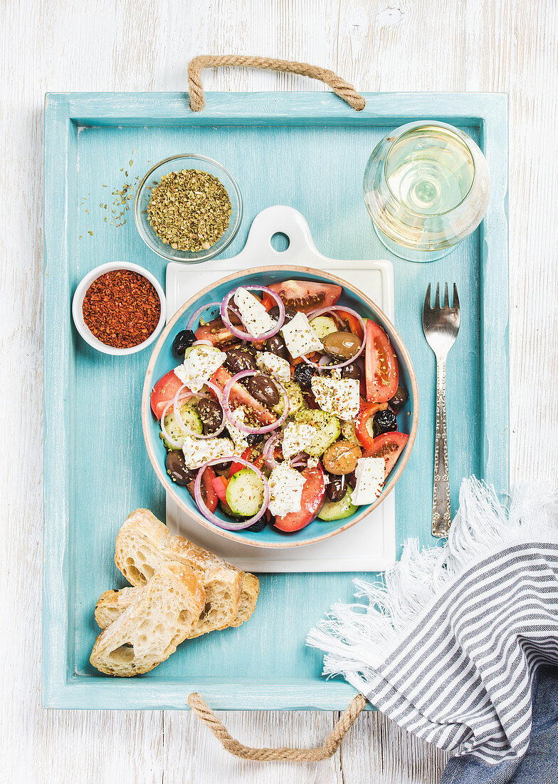 Greek salad with bread slices, oregano, pepper and glass of white wine